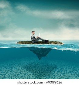 Business Man Work On Laptop Sitting On A Piece Of Land Floating In The Ocean.  Split Half-water Seascape.