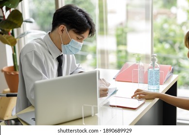 Business Man Workers Wearing Face Mask And Clear Shield Having Discussion Through Glass Partition At The Office As Part Of Business In New Normal During The Outbreak Of COVID-19 Or Coronavirus