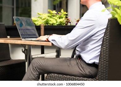 Business Man Working And Analyzing Financial Figures On A Graphs On A Laptop Outside