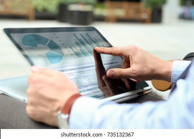 Business Man Working And Analyzing Financial Figures On A Graphs On A Laptop Outside