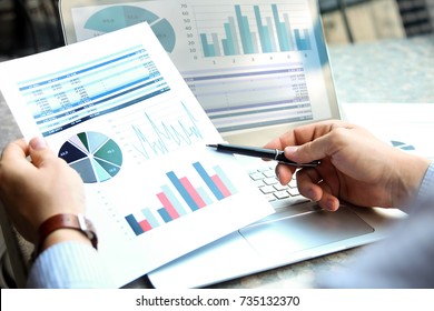 Business man working and analyzing financial figures on a graphs on a laptop outside - Shutterstock ID 735132370