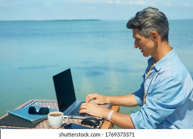 Business Man Working The Beach At Morning By The Sea, Using Laptop. Freedom, Remote Work, Freelancer, Technology, Internet, Travel And Vacation Concepts