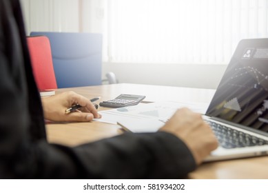 Business man working on his wooden table in the office with calculator,document,smart phone,pen and laptop in business,finance and banking concept