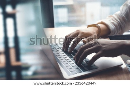 Business man working on laptop computer, hand typing on laptop keyboard on office table, surfing the internet, online job, online study, e-learning, working at home, telecommuting concept, close up