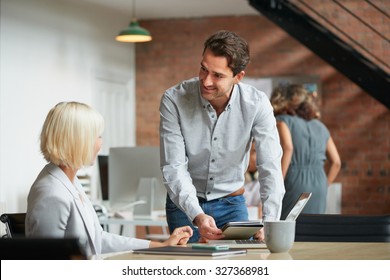 Business Manager Discussing Work With Colleague In Busy Office Studio