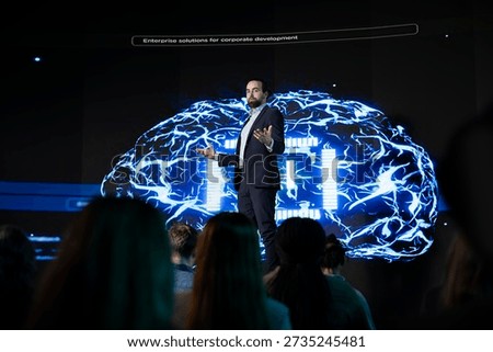Business manager hosting artificial intelligence presentation during convention event in auditorium, takes the stage for AI systems sales pitch. Presenter shows machine learning tech.
