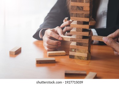 The business man's hand is planning a business strategy, the businessman plays the wooden block tower,Plans and strategies in the concept of a risky business