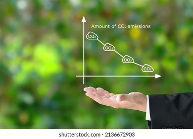 Business man's hand raising amount of CO2 emissions graph