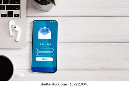 Business marketing Concept. Smartphone with newsletter subscription form and opened envelope icon on screen flat lay on table, creative collage for digital communication, top view with copy space
