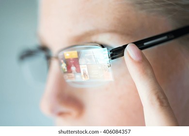 Business, Media, Future Technology, Information And People Concept - Close Up Of Woman In Eyeglasses With Virtual Screen Projection Pointing Finger To Earpiece