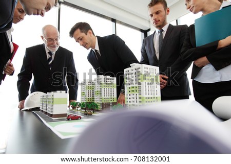 Business meeting of architects and investors looking at model of residential quarter houses