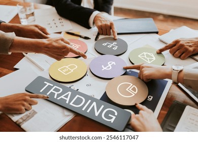 Business meeting with diverse hands pointing at trading symbols. Trading concepts, teamwork, and financial planning. Collaborative trading strategy session. - Powered by Shutterstock