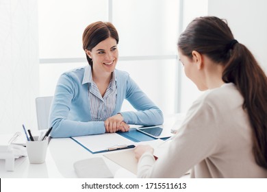 Business meeting in the office: a businesswoman is talking and checking a contract with the customer