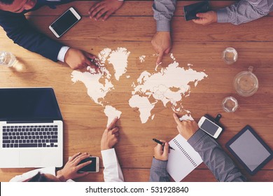 Business meeting on the wooden table.
working area. Hand pointing to your message. (World map from NASA) - Powered by Shutterstock