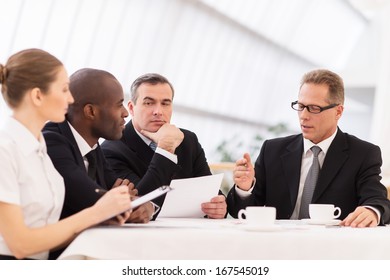 Business Meeting. Business People In Formalwear Discussing Something While Sitting Together At The Table