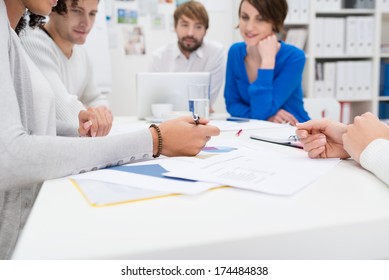 Business Meeting In Progress In The Office With A Low Angle View Down The Length Of The Table Of A Diverse Group Of Young Businesspeople Sitting Talking