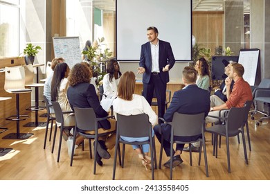 Business meeting. Serious business group leader instructing team, telling project strategy and presenting tasks. Confident man is talking to colleagues sitting in circle at meeting in office. - Powered by Shutterstock