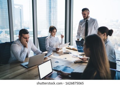 Business meeting at table in light office with executive male standing and speaking about working process and results to colleagues  - Shutterstock ID 1626875065