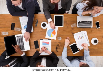 Business Meeting Top View. Multiethnic People Work In Office, Above View Of Wooden Table