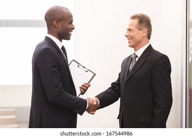 Business Meeting. Two Cheerful Business Men Shaking Hands And Looking At Each Other