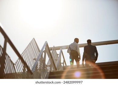 Business, men and walking on stairs in city for commute to work with communication, flare and low angle. People, back and travel together on steps outdoor for conversation, networking and partnership - Powered by Shutterstock