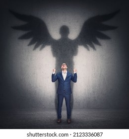 Business metaphor with a person casting a hero shadow on the wall. Powerful superhero or guardian angel with wings. Inner strength and ambition, leadership and personal development concept