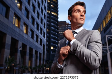 Business in the metropolis. A handsome businessman in a suit standing in a city setting at night.