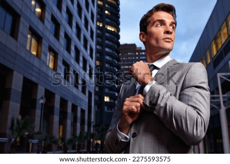 Business in the metropolis. A handsome businessman in a suit standing in a city setting at night.