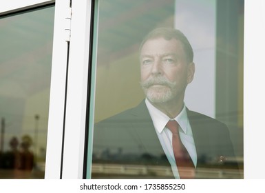 Business Middle Aged Man In Suit Thinking  And Looking Away By The Window Searching Or Waiting For His Family, Friend Or Partnership. Home Alone. Work Form Home.Home Alone.