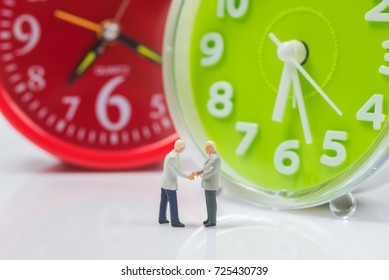 Business Miniature People Shaking Hands On Alarm Clock Background