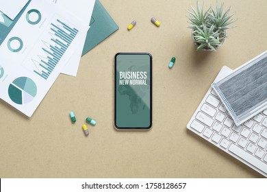 Business New Normal After Covid 19 Outbreak Background Concept. Mockup Mobile Phone For Covid19 Business New Normal With Facial Mask, Medicine Tablet, Financial Chart On Working Table.