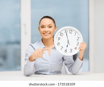business, office, school and education concept - attractive businesswoman pointing finger to clock