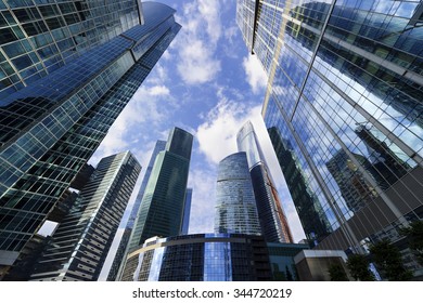 Business office skyscrapers, looking up at high-rise buildings in commercial district, architecture raising to the blue sky with white clouds, bottom view 