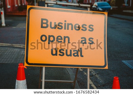 Business open as usual. Yellow sign stating business open as usual during lockdown and road works. Business open as usual sign on road. Business open as usual sign during coronavirus covid-19 pandemic