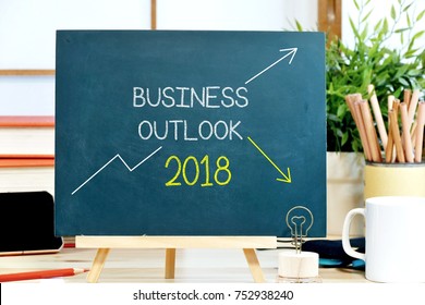 Business Outlook 2018 With The Trend Chart Both Up Trend And Down Trend Wrote On The Chalkboard With The Background Of Workspace In The Office