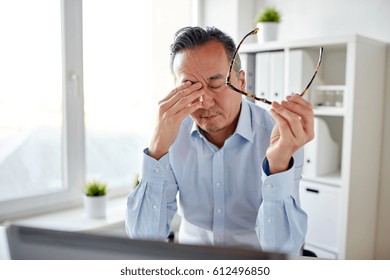 business, overwork, deadline and people concept - tired businessman with eyeglasses and laptop computer rubbing eyes at office