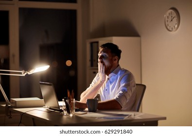 business, overwork, deadline and people concept - tired man with laptop working at night office and yawning - Shutterstock ID 629291840