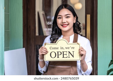 Business owner happy beautiful young asian woman in apron looking at camera, we're open sign on front door smiling welcoming clients to new cafe, People and start-up concept. - Powered by Shutterstock