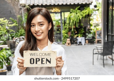 Business owner happy beautiful young asian woman in apron looking at camera, we're open sign on front door smiling welcoming clients to new cafe, People and start-up concept. - Powered by Shutterstock