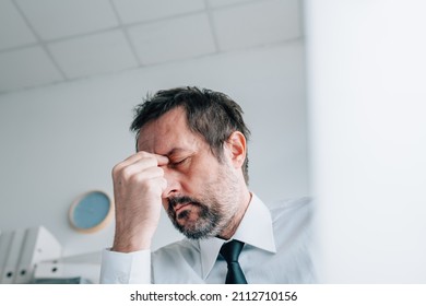 Business owner headache concept, businessman with painful migraine in office, selective focus
