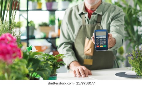 Business Owner In His Flower Shop, He Is Holding A POS Payment Terminal, Cashless Electronic Payments Concept