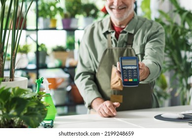 Business Owner In His Flower Shop, He Is Holding A POS Payment Terminal, Cashless Electronic Payments Concept