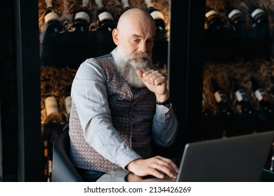 Business Owner Of A Liquor Store Sitting In Front Of An Open Laptop .