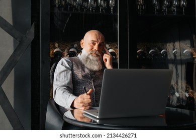 Business Owner Of A Liquor Store Sitting In Front Of An Open Laptop .