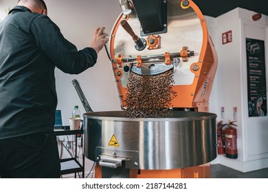 Business Owner Pouring Freshly Roasted Coffee Beans From Large Coffee Roaster Into Cooling Cylinder