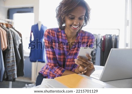 Business owner using cell phone in clothing shop