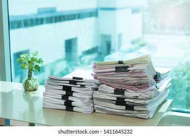 Business papers and documents stack on desk in office.