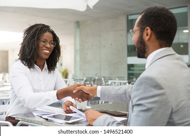 Business partners closing deal in coffee shop. Business man and woman meeting in street cafe and shaking hands with each other. Agreement or handshake concept