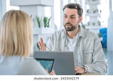 Business partners at a coffee shop working on a laptop computer. Friends sitting at a coffee table with laptop and notepads doing work. Teamwork, cooperation and team spirit - Powered by Shutterstock