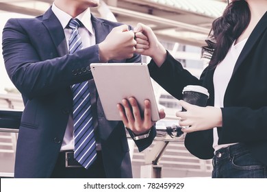 Business Partners Giving Fist Bump after complete a deal on cityscape background. Happy Successful Teamwork Partnership closing the deal. Businessman with tablet giving fist bump to businesswoman.